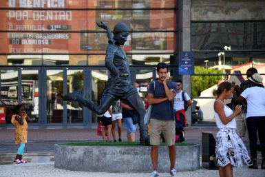 Football fans take pictures next to the statue of Portugal legend Eusebio outside Benfica's Estadio da Luz, which will host the Champions League final on August 23
