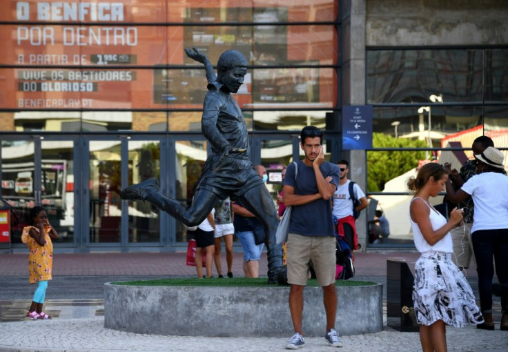 Football fans take pictures next to the statue of Portugal legend Eusebio outside Benfica's Estadio da Luz, which will host the Champions League final on August 23