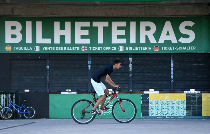 A cyclist rides in front of the locked ticket office at the Estadio Jose Alvalade, one of the Champions League 'Final Eight' venues