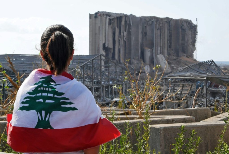 A Lebanese youth wrapped in the national flag looks at the damaged grain silos at Beirut's port, where a huge chemical explosion devastated large swathes of the capital