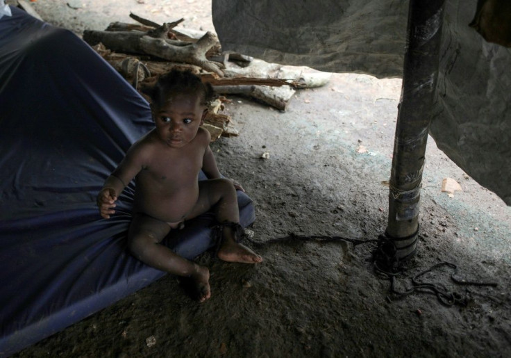 A baby is tied to a post to keep her from crawling away at the migrant camp in La Penita, Panama, which is home to around 1,500 migrants