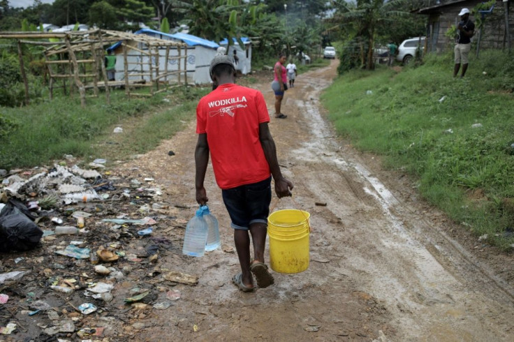 A migrant collects water from a broken pipe in La Penita, Panama, where 1,500 migrants are stuck due to the coronavirus pandemic