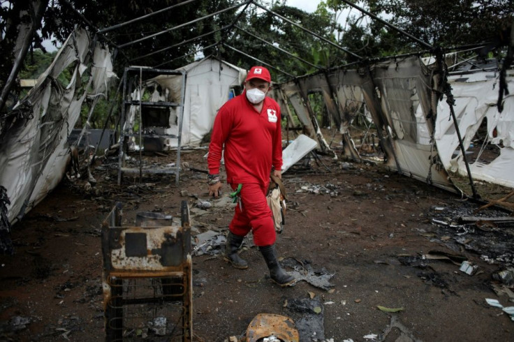 A Red Cross worker walks around a burnt-out tent that was set alight by migrants angry that they're being prevented from continuing to Mexico and the US