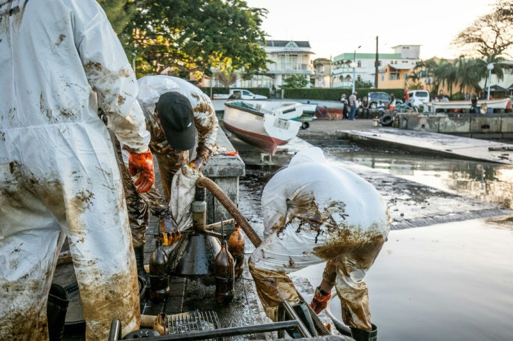 Fishermen and skippers tend to a pump that has been pressed into service to extract the oil