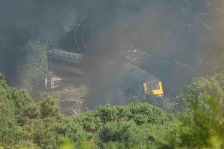With smoke rising, derailed carriages lie at the scene of a train crash near Stonehaven in northeast Scotland. Police say three people died.