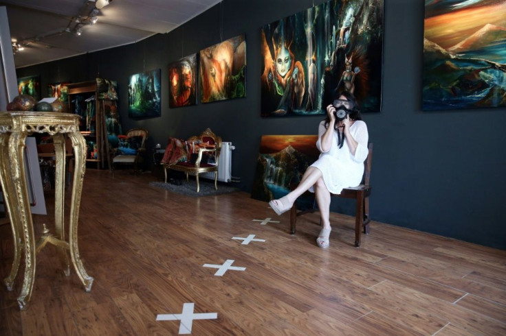 Artist Sylvia Reijbroek, who owns an art gallery, wears a face mask on the Belgian side of her shop, marked out by white crosses, because Belgium makes face coverings compulsory to fight the coronavirus