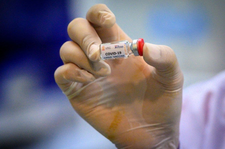 A laboratory technician holds a dose of a COVID-19 vaccine