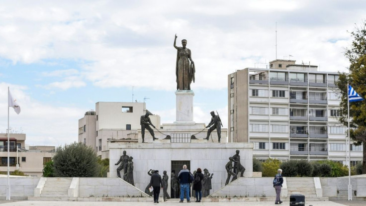 Tourists stand before the "Liberty Monument" in the Cypriot capital Nicosia, erected to honour the fighters in the 1955-1959 conflict for independence from Britain