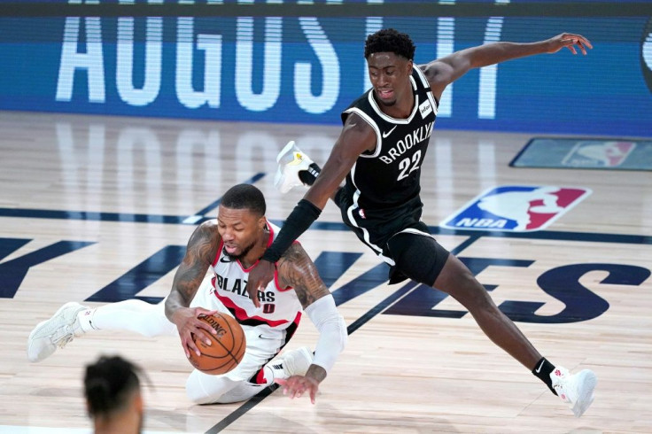 Portland's Damian Lillard falls while chasing the ball against Brooklyn's Caris LeVert in the Trail Blazers' 134-133 NBA victory over the Nets
