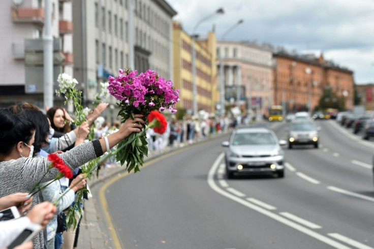 Women with flowers stand along a street as they protest against police violence during recent rallies of opposition supporters, who accuse strongman Alexander Lukashenko of falsifying the polls in the presidential election.