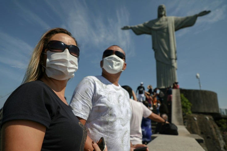 Tourists wearing face masks against the coronavirus enjoy the view from the base of Rio de Janeiro's iconic Christ the Redeemer statue on August 15, 2020 as the city reopened some tourist attractions closed months ago