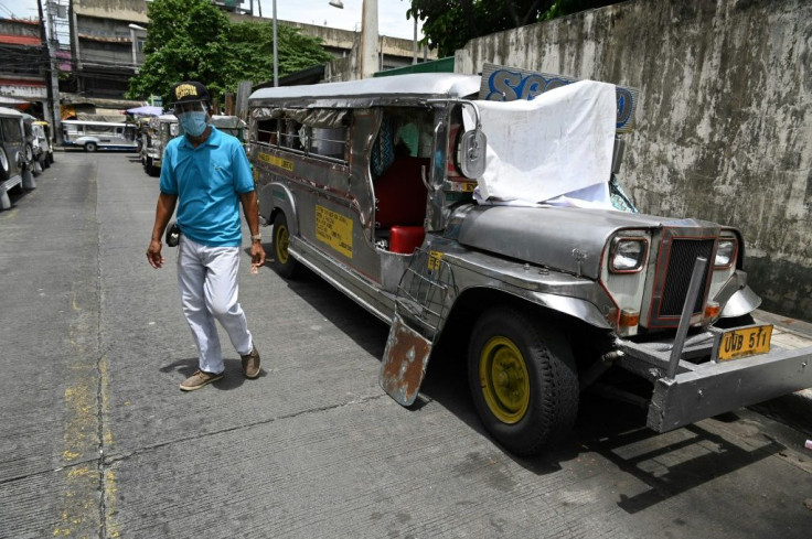 A resident walks past jeepneys serving as temporary homes parked along a road in Manila