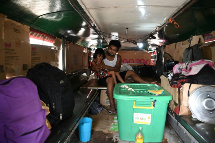 Jeepney driver Daniel Flores attends to one of his children inside their vehicle, which has become a temporary shelter
