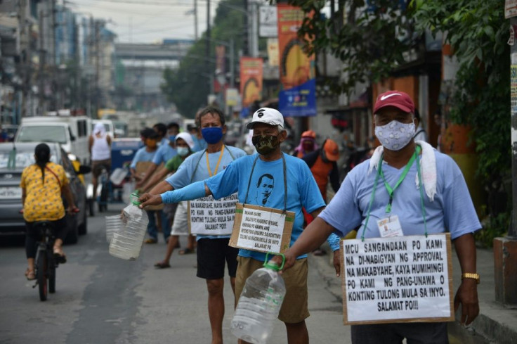 A group of jeepney drivers begging for cash, whose placards read: 'Mam/sir, we're jeepney drivers, asking for your help'