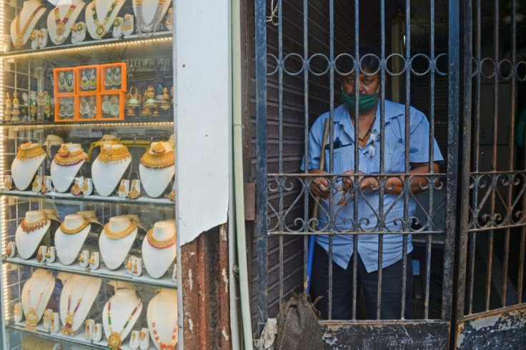 A guard stands behind an iron gate beside a gold jewellery shop in Mumbai