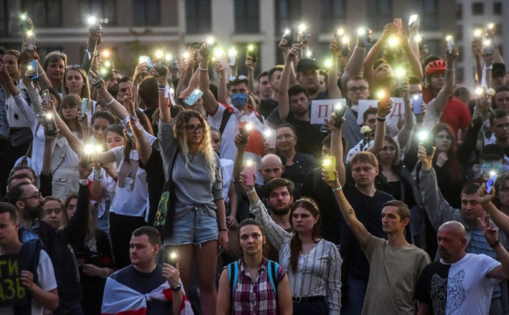 Belarus opposition supporters raise their mobile phones during a minute of silence near the state TV and radio company