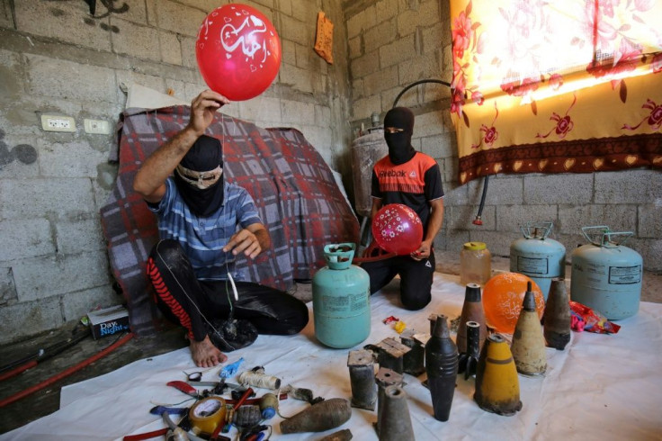 Masked Palestinians prepare flammable objects before attaching them to balloons to be flown toward Israel, in Rafah in the southern Gaza Strip, on August 8