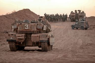 Israeli infantry soldiers gather next to tanks and an armoured personnel carrier near the Israeli border with the Gaza Strip on Sunday