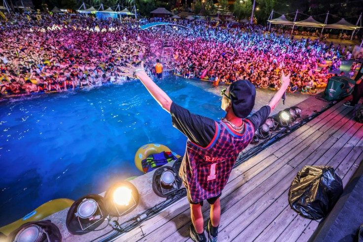 A performer in a stage show at the front of the water waved at the crowd, packed close and waving their arms back