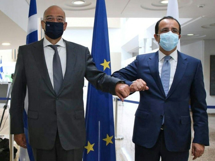 Cypriot Foreign Minister Nicos Christodoulides (R) greets with an elbow bump his Greek counterpart Nikos Dendias in Nicosia