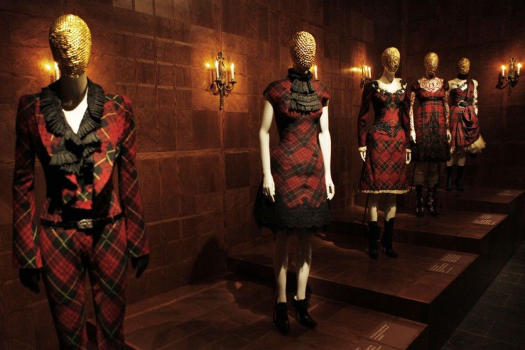 Visitors look through a glass display case at creations by the late British designer Alexander McQueen during a preview at the Metropolitan Museum of Art in New York