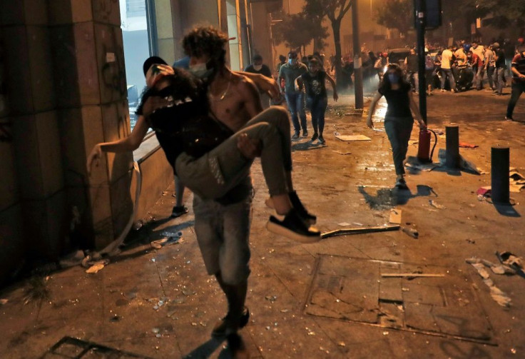 A Lebanese protester carries a wounded demonstrators to safety at the headquarters of the Lebanese association of banks in downtown Beirut on August 8, 2020, following a demonstration against a political leadership they blame for a monster explosion that