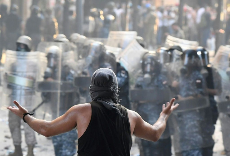 A Lebanese protester gestures towards security forces during clashes in downtown Beirut on August 8, 2020, following a demonstration against a political leadership they blame for a monster explosion that killed more than 150 people and disfigured the capi