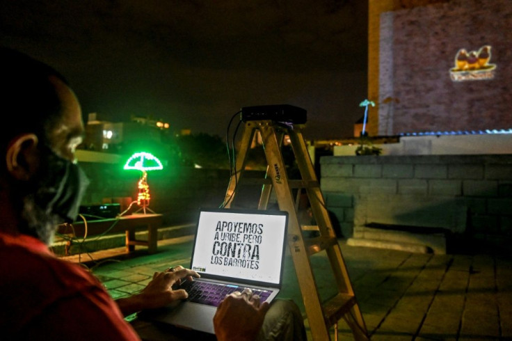 An activist uses a laptop to project an image on a building in Medellin