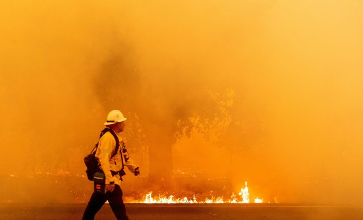 A Pacific Gas and Electric firefighter walks down a road as flames approach in Fairfield, California during the LNU Lightning Complex fire on August 19, 2020
