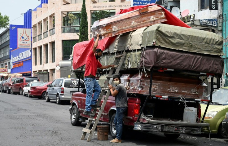 Workers unload coffins from a truck outside a funeral home located in front of the General Hospital in Mexico City