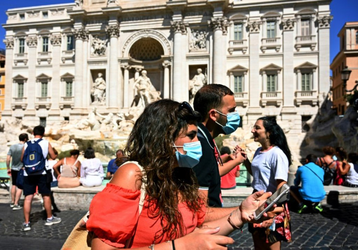 Tourists wearing face masks walk by the Trevi fountain in Rome. Italy, France, Spain and Germany have seen a spike in virus cases as the pandemic rebounds across Europe -- often due to travel, summer holidays and parties