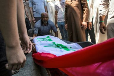 Mourners gather around the Iraqi flag draped coffin of slain activist Riham Yaaqub during her funeral in the city of Basra on Thursday