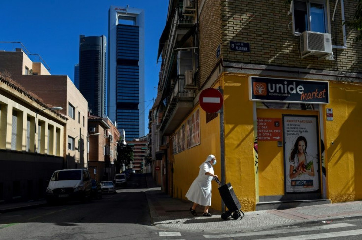 A nun wearing a facemask pushes a trolley in the outskirts of Madrid with the Cuatro Torres business area in the background