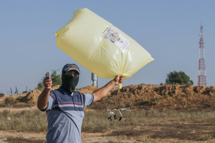 A Palestinian uses a phone to film himself holding an inflated plastic bag attached to an incendiary device before releasing it toward Israel