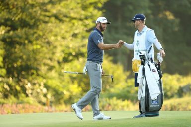 Dustin Johnson, left, bumps fists with his caddie and brother Austin Johnson after making a 40-foot eagle putt on the 18th hole Saturday to seize a five-stroke lead after three rounds at the US PGA Northern Trust tournament