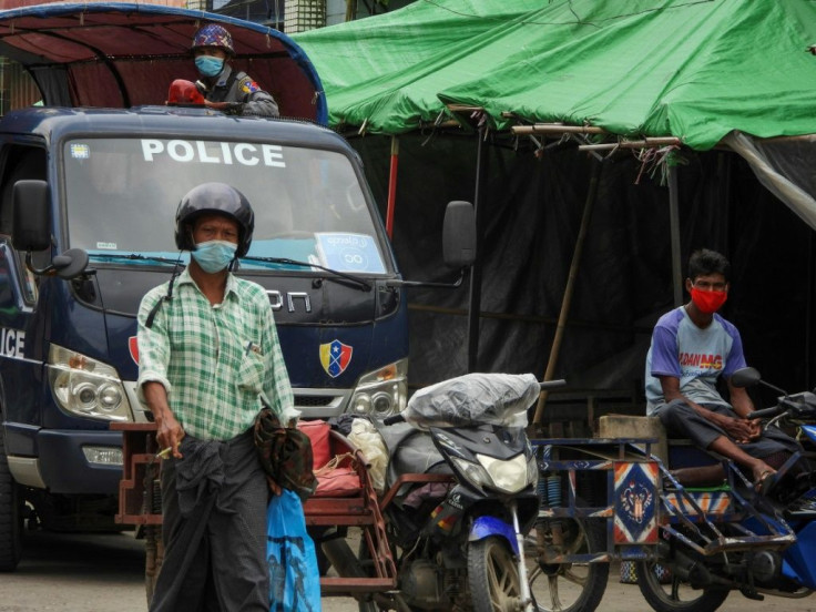 A police officer watches from a vehicle while people wear face masks during the Sittwe lockdown