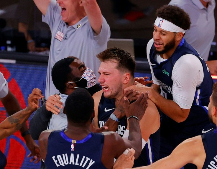 Luka Doncic of the Dallas Mavericks is mobbed by teammates as they celebrate his game-winning three-point basket against the LA Clippers at the buzzer in overtime