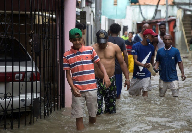 Men wade through a flooded street in Santo Domingo after Tropical Storm Laura caused destruction in the Dominican capital