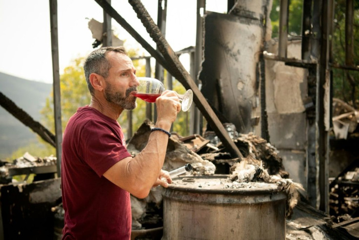 La Borgata Winery owner Gerry Iulano tastes wine from a burned barrel amidst the charred remains of his winery during the LNU Lightning Complex fire in Vacaville, California on August 23, 2020