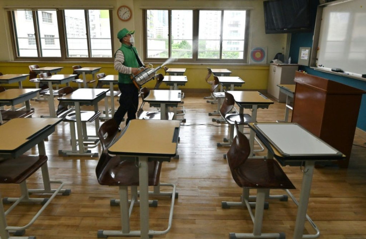 A worker sprays disinfectant in a classroom at a high school in Seoul