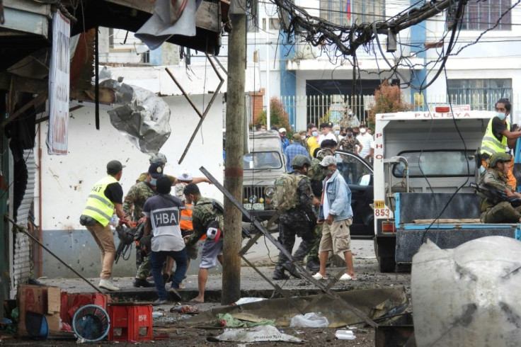 Military personnel and civilians stretcher away a soldier after the bombs in Jolo