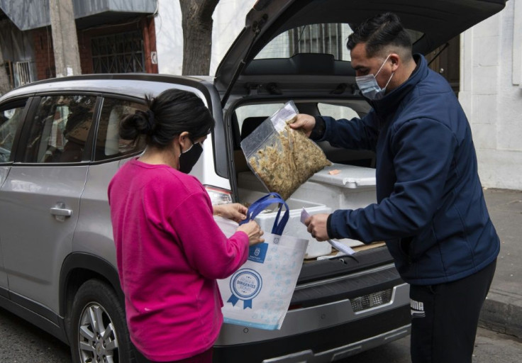 A city worker hands out a meal for a needy woman in Santiago