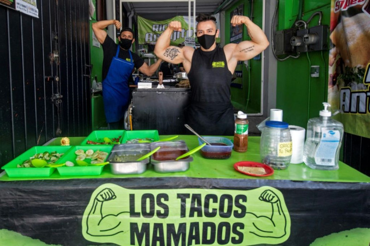 Mexican Ulises Perez, 36, and Gustavo Contreras, 30, pose as they work at a taco restaurant set up at a closed gym in Mexico City, on August 17, 2020, amid the coronavirus pandemic