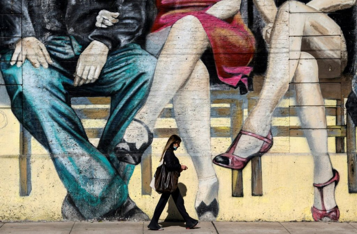 A woman walks past a mural featuring tango dancers in Buenos Aires