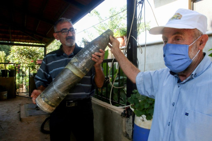 A resident of the Lebanese village of Hula shows what he says is an unexploded Israeli munition fired across the border during the flare-up