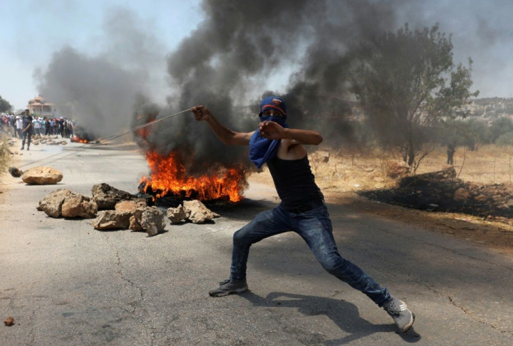 A Palestinian youth hurls a stone towards Israeli forces in the village of Turmus Aya, north of Ramallah in the occupied West Bank, following a protest march by Palestinians against the building of Israeli settlements, on August 7