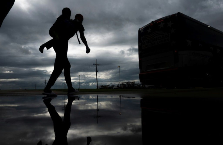 A man carries a child on his back as he walks to board an evacuation bus