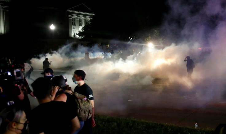Protesters run as police shoot teargas in an effort to disperse demonstrations against the shooting of Jacob Blake in Kenosha, Wisconsin on August 25, 2020, with Facebook saying it has removed accounts linked to the violence