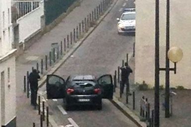 Hooded gunmen Cherif Kouachi and his brother Said Kouachi face police officers near the offices of the French satirical newspaper Charlie Hebdo in Paris, during the attack