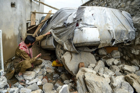 A villager inspects a damaged car among the debris of houses after a flash flood hit Charikar